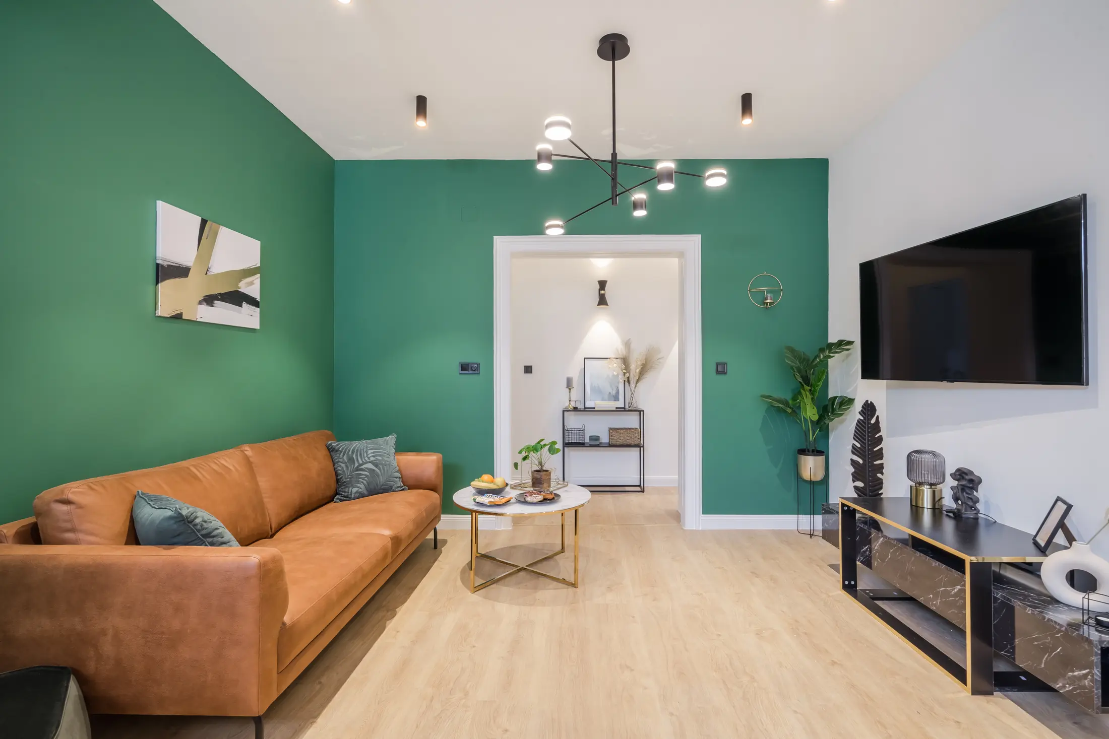 Séjour livré avec murs verts, canapé en cuir et nouvel éclairage