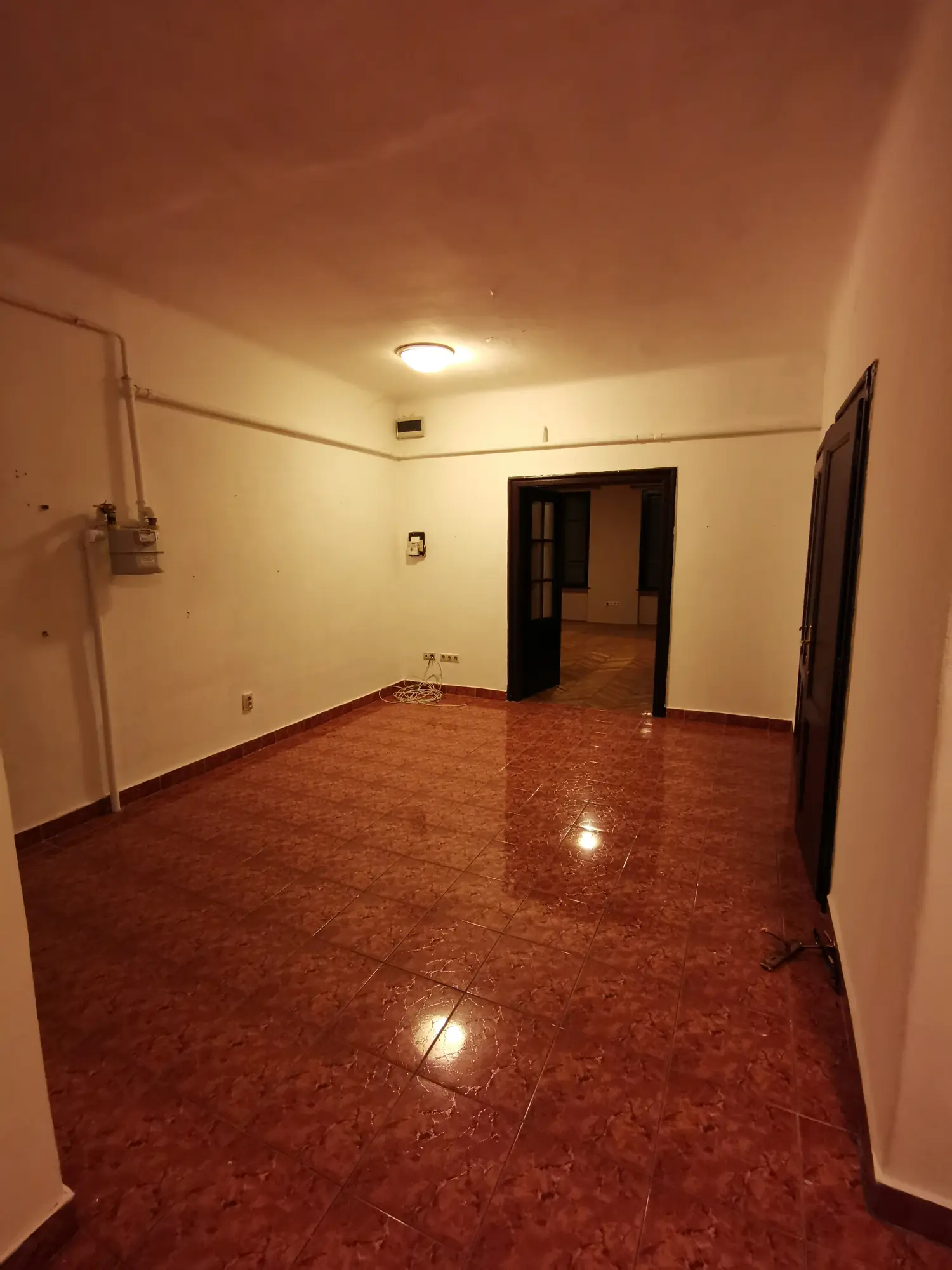 Séjour de l’appartement avant rénovation, avec ancien sol et réseaux apparents